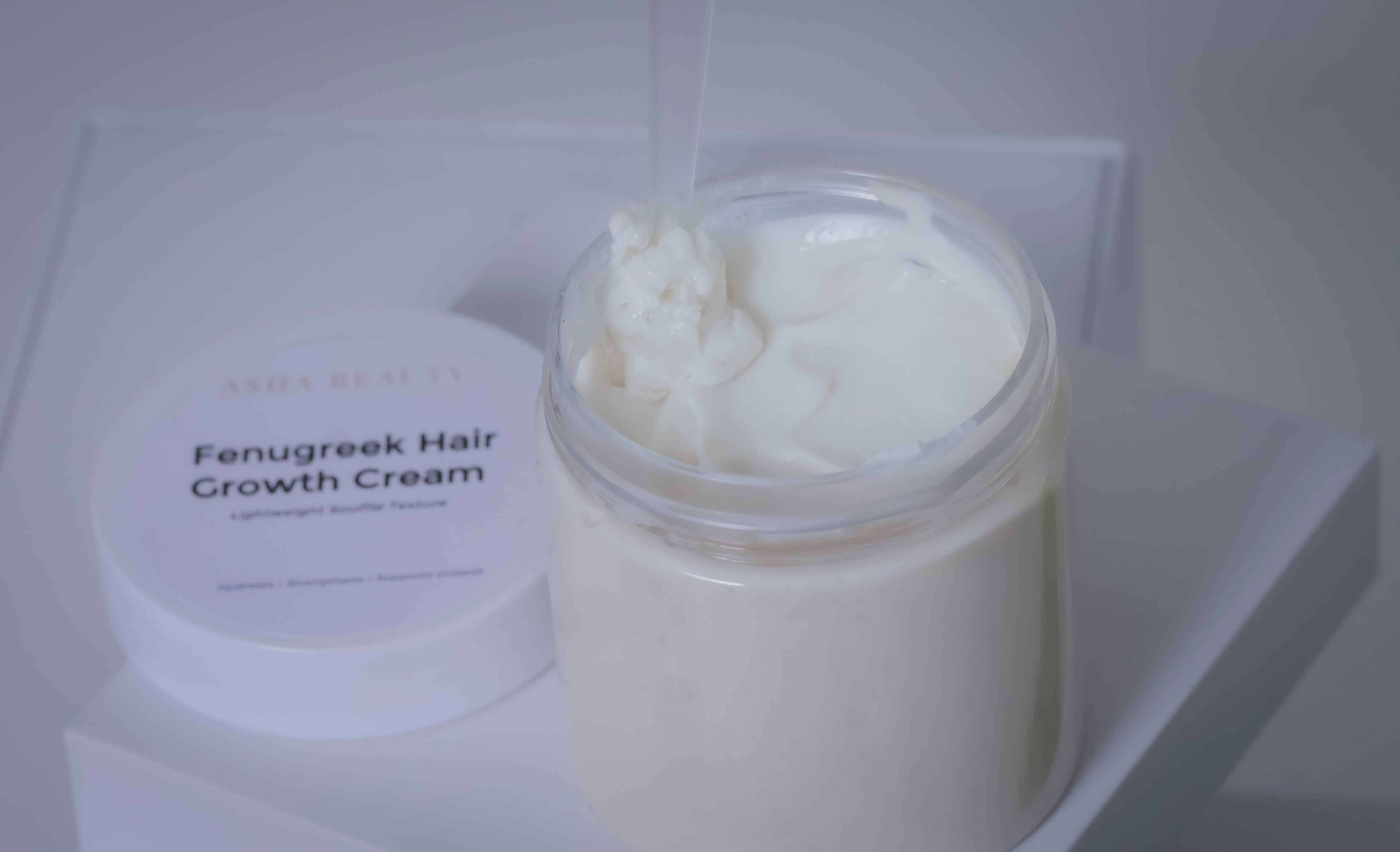 Asha Belle Beauty Fenugreek Hair Growth Cream jar with a white lid on a light gray background
