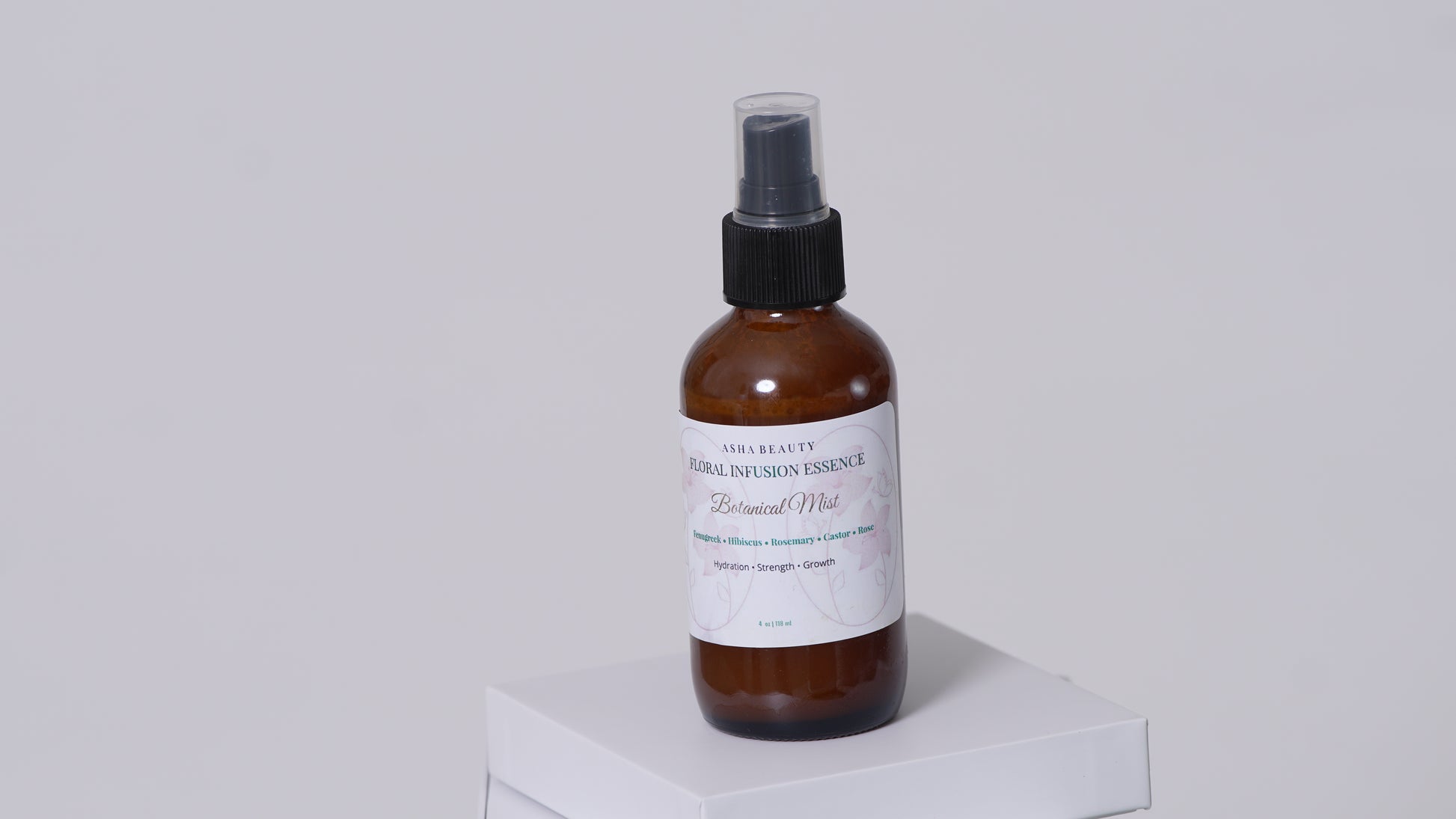 Asha Belle Beauty Floral Infusion Botanical Mist amber bottle on white pedestal, natural curl care hair spray 4 fl oz